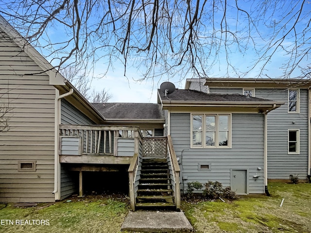 rear view of house with a wooden deck and a lawn