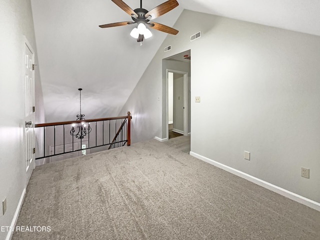 carpeted empty room with ceiling fan with notable chandelier and high vaulted ceiling