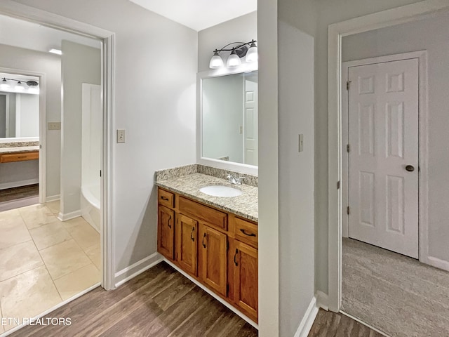 bathroom featuring vanity, a bath, and wood-type flooring