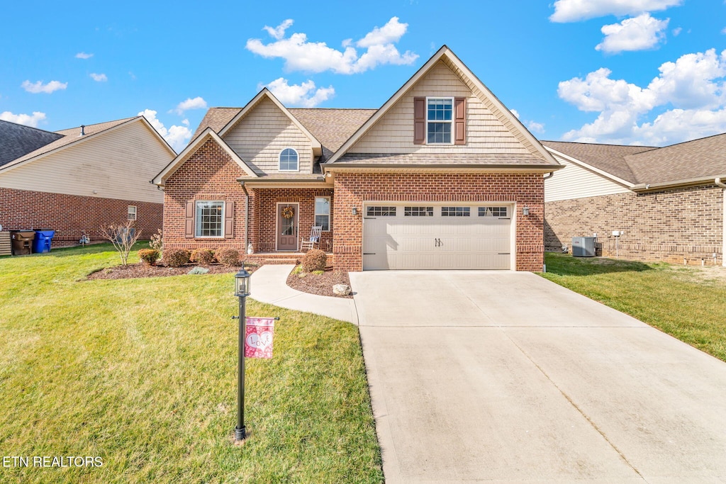 view of front of home with a garage, central AC unit, and a front yard