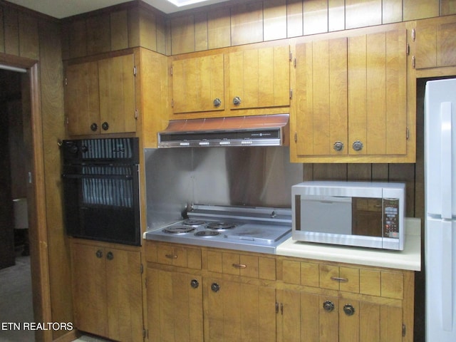 kitchen featuring ventilation hood, white fridge, oven, and cooktop