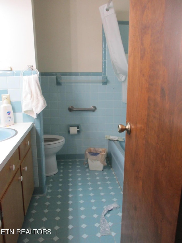 bathroom featuring vanity, tile walls, a washtub, and toilet