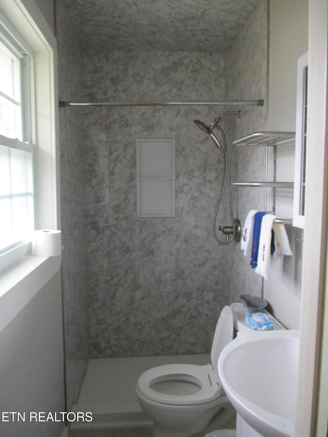 bathroom with sink, toilet, and tiled shower