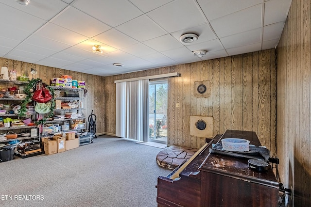 carpeted home office with a drop ceiling and wood walls