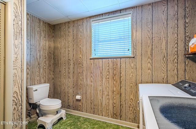 bathroom featuring washer / dryer, wood walls, and toilet