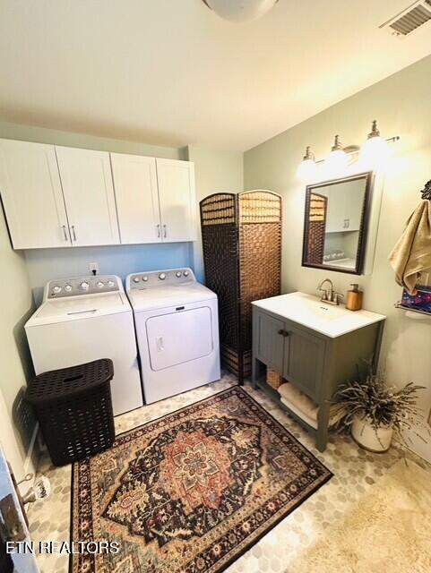 clothes washing area with cabinets and washer and dryer