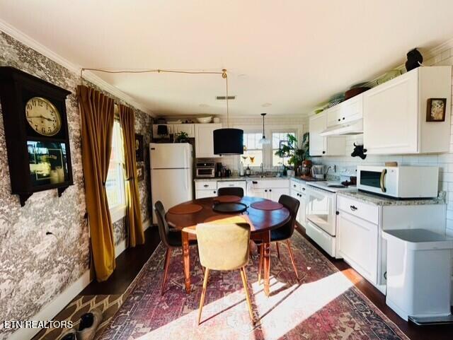 kitchen with white appliances, hanging light fixtures, and white cabinets