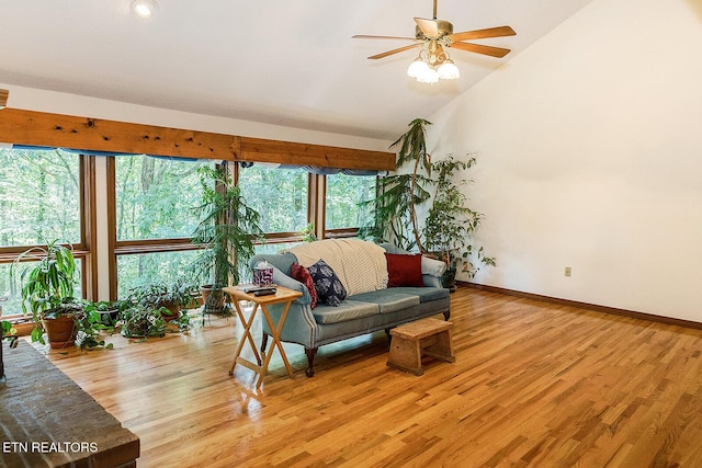 living area with high vaulted ceiling, a ceiling fan, light wood-style flooring, and baseboards