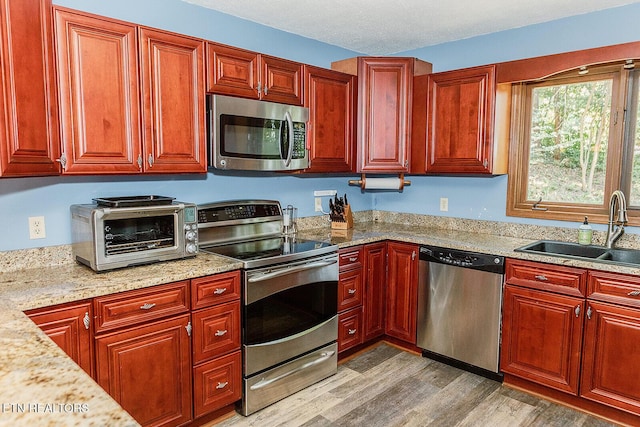 kitchen featuring a toaster, a sink, dark brown cabinets, appliances with stainless steel finishes, and light wood-type flooring