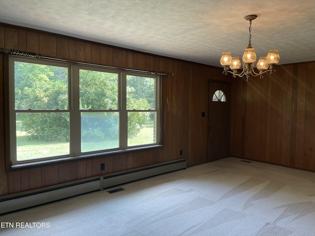 carpeted spare room with wood walls, a textured ceiling, and baseboard heating