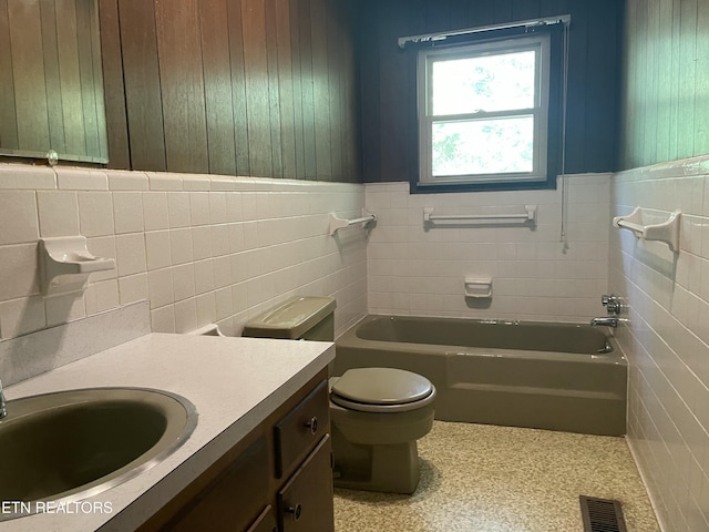 bathroom featuring vanity, a tub, tile walls, and toilet