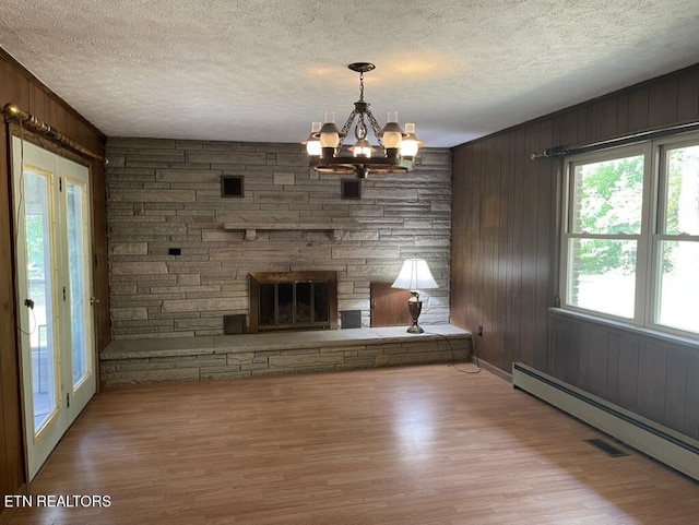 unfurnished living room featuring a stone fireplace, a baseboard radiator, and light wood-type flooring