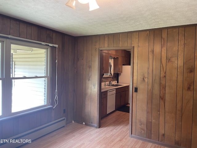 empty room with a baseboard radiator, light hardwood / wood-style flooring, and a textured ceiling