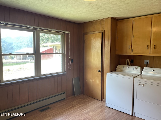 clothes washing area featuring cabinets, a textured ceiling, washer and clothes dryer, light hardwood / wood-style floors, and a baseboard heating unit