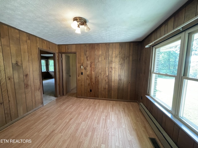 empty room featuring light hardwood / wood-style flooring, plenty of natural light, and baseboard heating