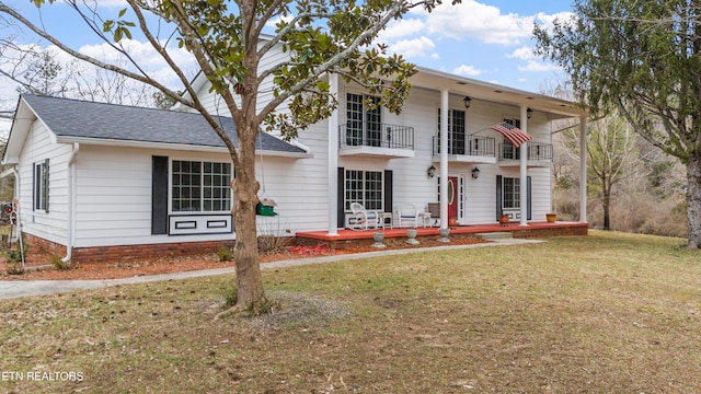 view of front of property with a balcony, covered porch, and a front lawn