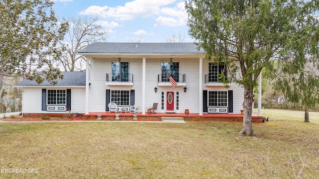 view of front of property featuring a balcony and a front yard