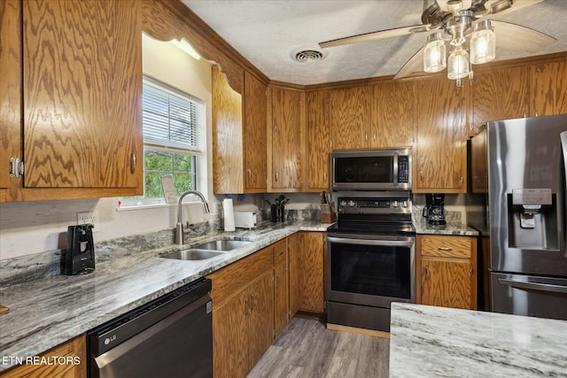 kitchen with visible vents, appliances with stainless steel finishes, brown cabinets, and a sink