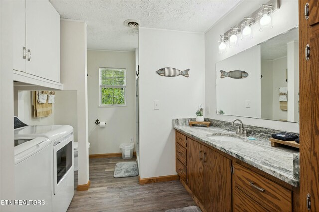 bathroom featuring a textured ceiling, wood finished floors, vanity, visible vents, and washer and dryer