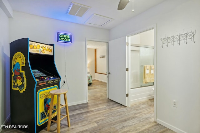 recreation room with wood finished floors, a ceiling fan, baseboards, visible vents, and attic access