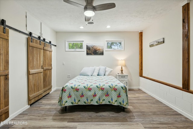 bedroom featuring a textured ceiling, a barn door, and light wood-type flooring