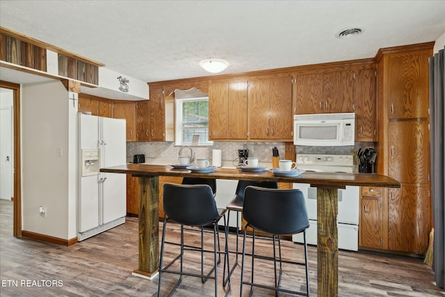 kitchen with tasteful backsplash, white appliances, and wood finished floors