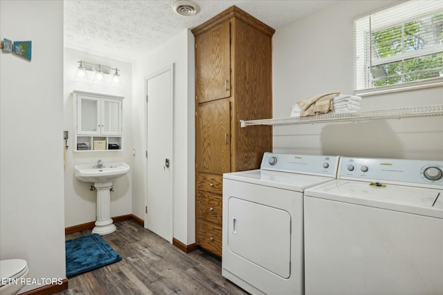 clothes washing area featuring laundry area, visible vents, washer and clothes dryer, wood finished floors, and a textured ceiling