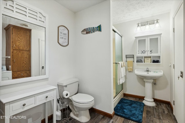 full bathroom with toilet, wood finished floors, baseboards, a shower stall, and washer / dryer