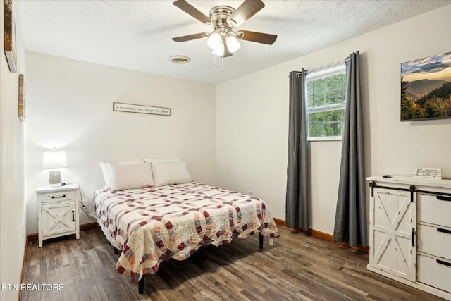 bedroom with dark wood-style floors, a textured ceiling, visible vents, and baseboards