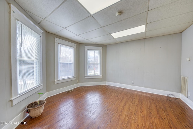 empty room with wood-type flooring and a paneled ceiling