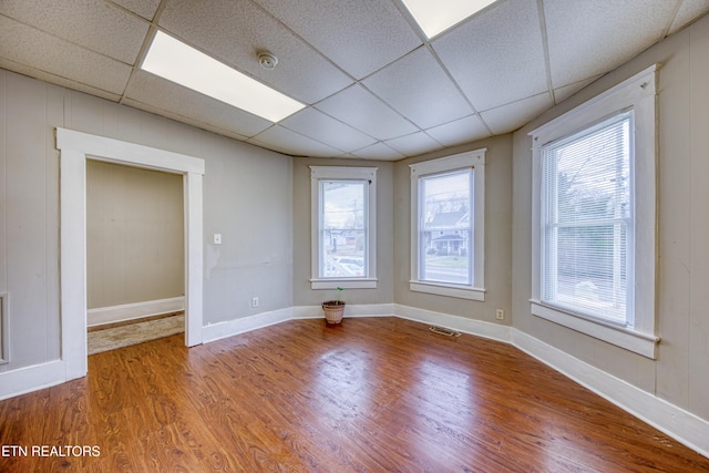 empty room featuring hardwood / wood-style flooring and a paneled ceiling