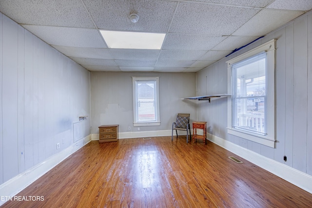 empty room with hardwood / wood-style flooring and a drop ceiling