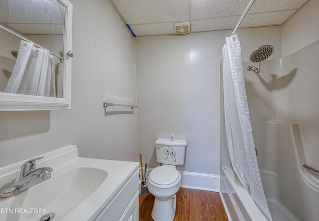 full bathroom featuring hardwood / wood-style floors, vanity, shower / tub combo, toilet, and a drop ceiling