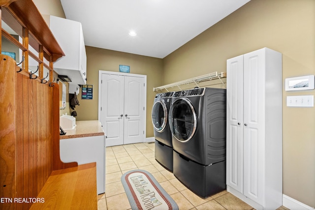 washroom featuring cabinets, light tile patterned flooring, and washing machine and clothes dryer