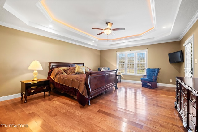 bedroom with a raised ceiling, ornamental molding, ceiling fan, and light wood-type flooring