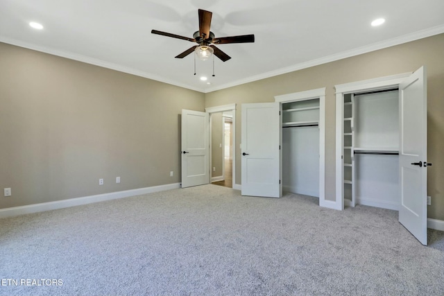 unfurnished bedroom with light colored carpet, ornamental molding, and two closets