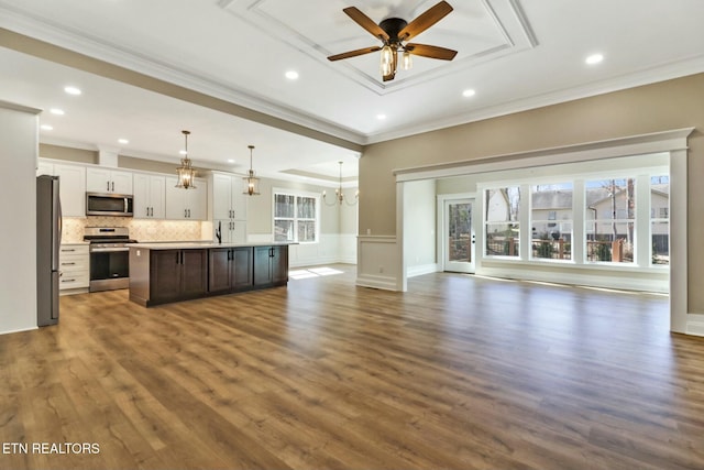 kitchen with appliances with stainless steel finishes, pendant lighting, white cabinets, a center island, and crown molding