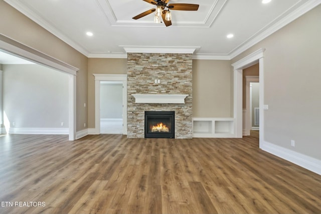 unfurnished living room featuring ceiling fan, ornamental molding, a stone fireplace, and hardwood / wood-style floors