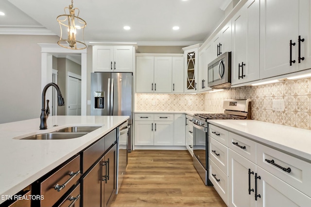 kitchen with stainless steel appliances, white cabinetry, sink, and pendant lighting