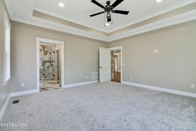 unfurnished bedroom with ornamental molding, carpet flooring, ensuite bathroom, and a tray ceiling