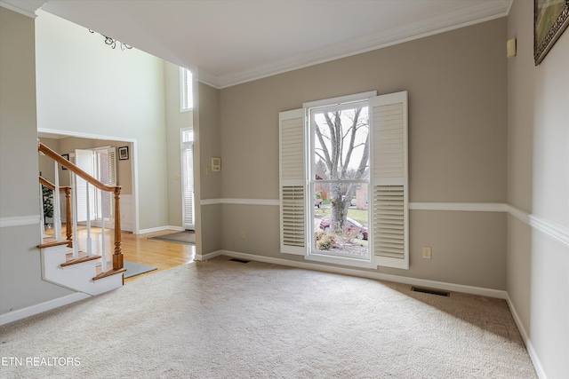 spare room with ornamental molding, a wealth of natural light, and light carpet