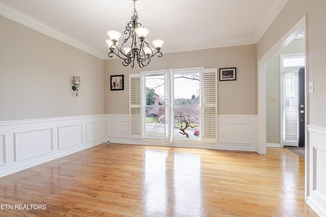 spare room featuring ornamental molding, a notable chandelier, and light hardwood / wood-style floors