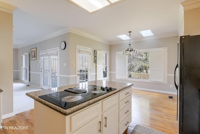 kitchen featuring a skylight, white cabinetry, a kitchen island, and black appliances