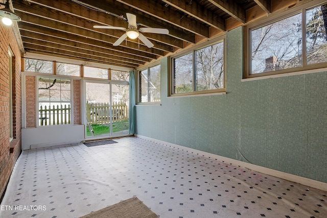 unfurnished sunroom featuring ceiling fan, beam ceiling, and a healthy amount of sunlight