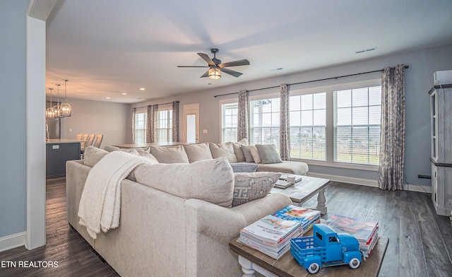 living room featuring ceiling fan with notable chandelier and dark hardwood / wood-style floors