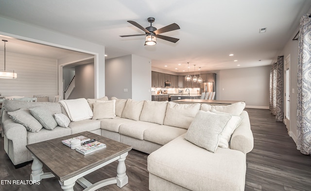 living room featuring ceiling fan with notable chandelier and dark hardwood / wood-style floors