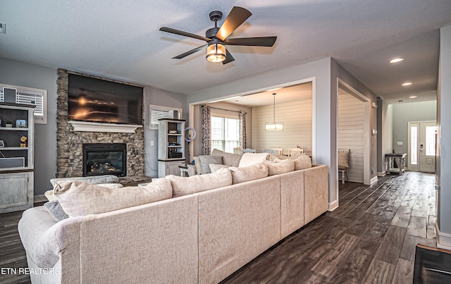 living room with ceiling fan, dark hardwood / wood-style floors, a textured ceiling, and a fireplace