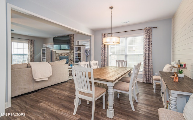 dining space featuring a stone fireplace and dark hardwood / wood-style flooring