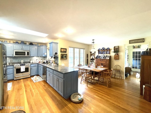 5001 Cheyenne Dr, Crossville, TN 38572 - kitchen featuring gas stove, white microwave, gray cabinetry, dishwashing machine, and light wood-style floors