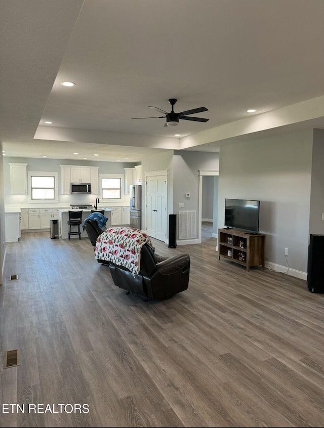 living room with ceiling fan, dark hardwood / wood-style floors, and a raised ceiling